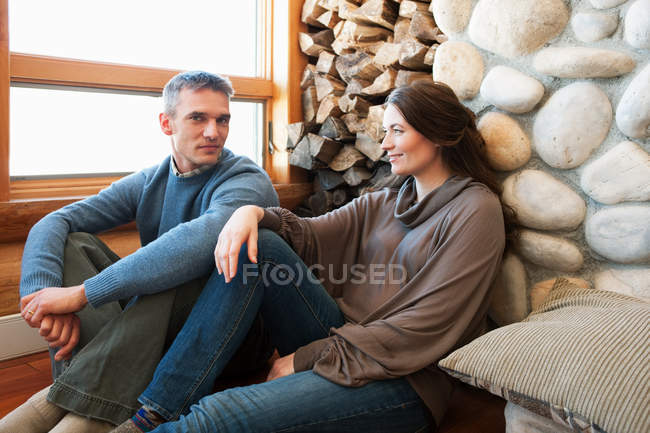 Portrait of adult couple sitting in log cabin — Stock Photo