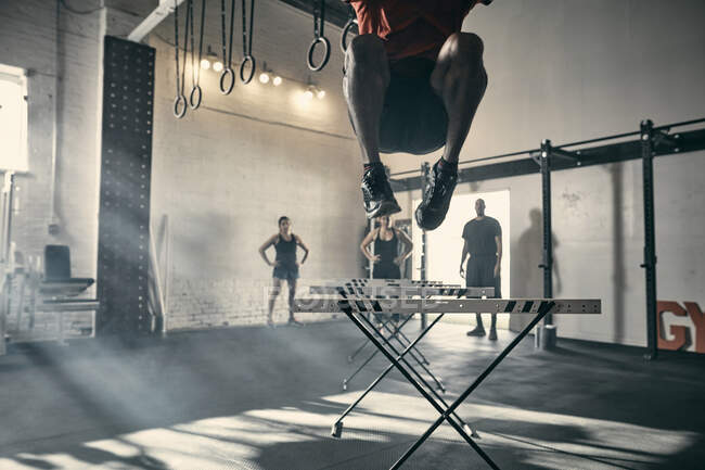 Человек в воздухе прыгает с барьерами в спортзале — стоковое фото