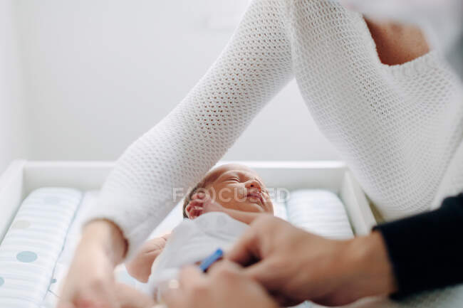 Mãe e pai vestir bebê recém-nascido — Fotografia de Stock