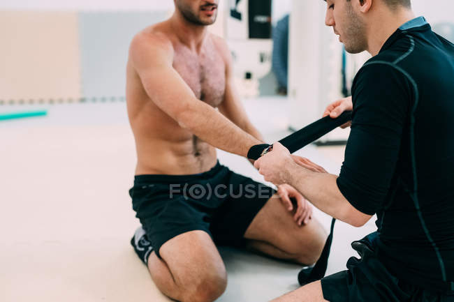 Coach wrapping boxer hand on floor — Stock Photo