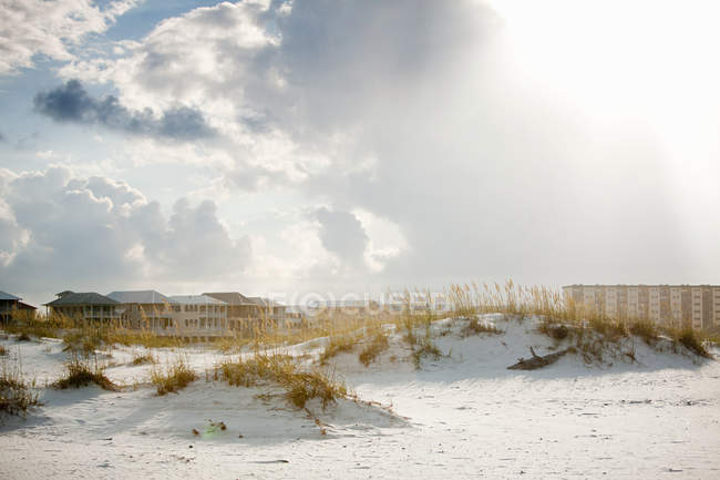 Vista de dunas de areia e casas contra o céu com nuvens — Fotografia de Stock