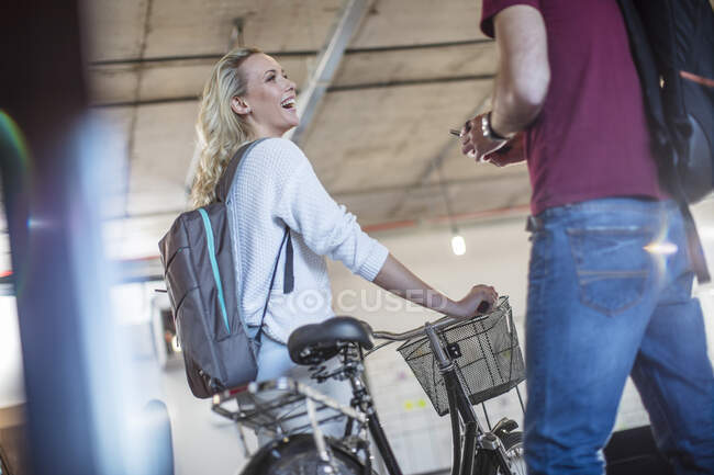 Mujer joven con colega de bienvenida en bicicleta en la oficina - foto de stock
