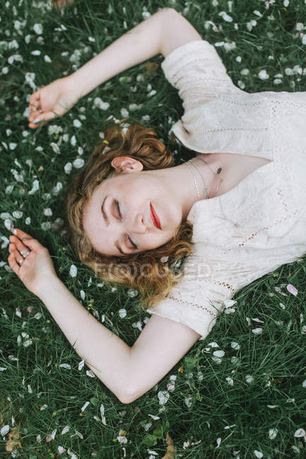 Donna sdraiata sull'erba coperta di fiori, vista aerea — Foto stock