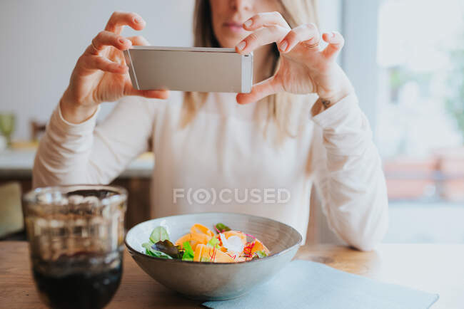 Donna che cattura foto di pasto vegano in ristorante — Foto stock