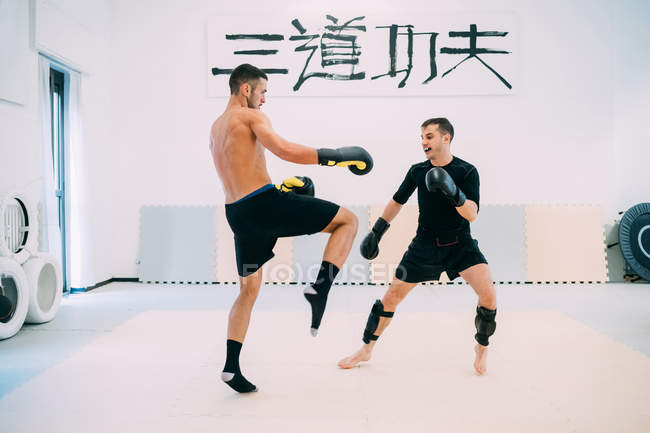 Men in boxing gloves sparring with personal trainer — Stock Photo