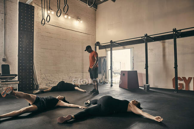 Викладач ґіму наглядає за людьми, які займаються вправами на підлогу в спортзалі. — стокове фото