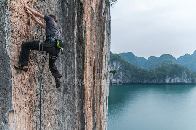 Hombre escalando en roca caliza, Ha Long Bay, Vietnam - foto de stock