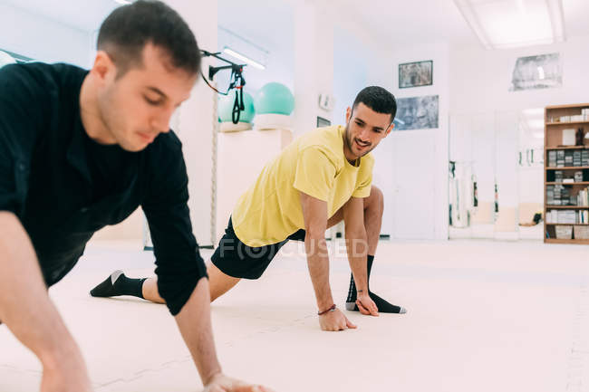 Чоловіки в спортзалі роблять розтяжки вправи — стокове фото