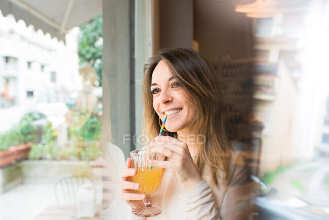 Mujer bebiendo por la ventana en el restaurante - foto de stock