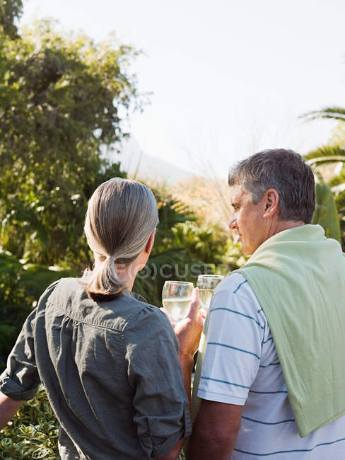 Couple with glasses of wine looking at view from garden — Stock Photo