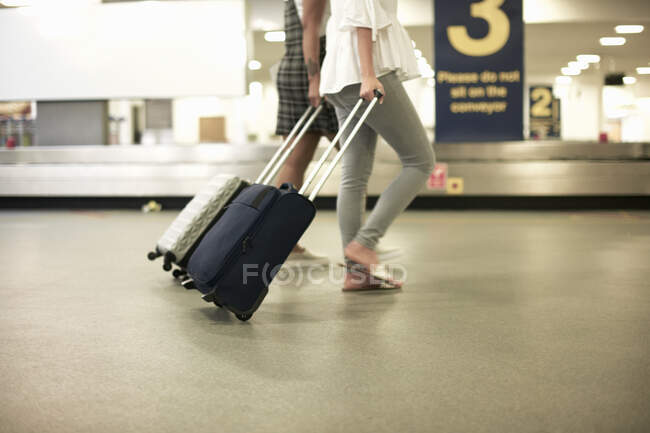 Друзья с чемоданами на колесах в аэропорту — стоковое фото