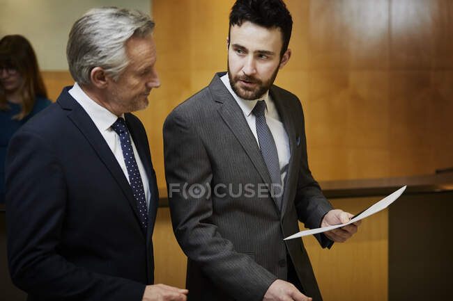 Two businessmen looking at paperwork in reception — Stock Photo