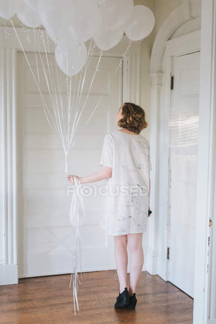 Mujer en apartamento sosteniendo montón de globos - foto de stock