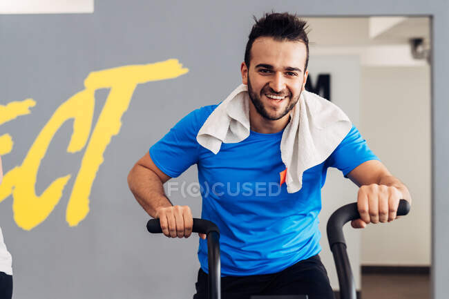 Чоловік у спортзалі використовує тренажерний велосипед — стокове фото