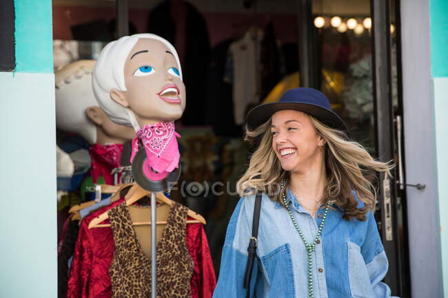 Молодая женщина покидает магазин одежды улыбаясь — стоковое фото