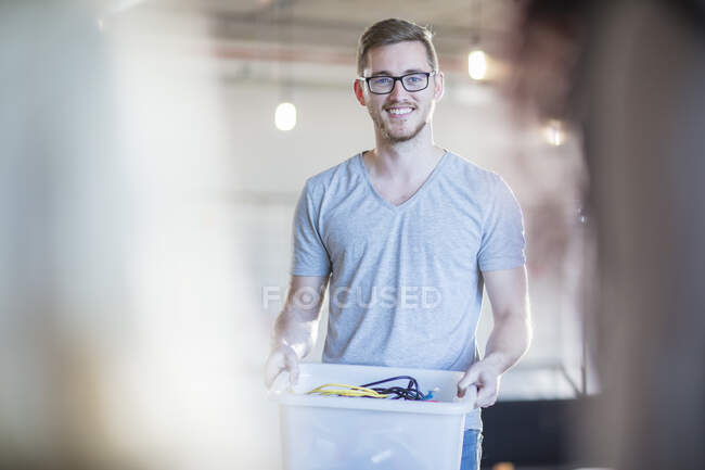 Computer technician with box of cables in office, portrait — Stock Photo