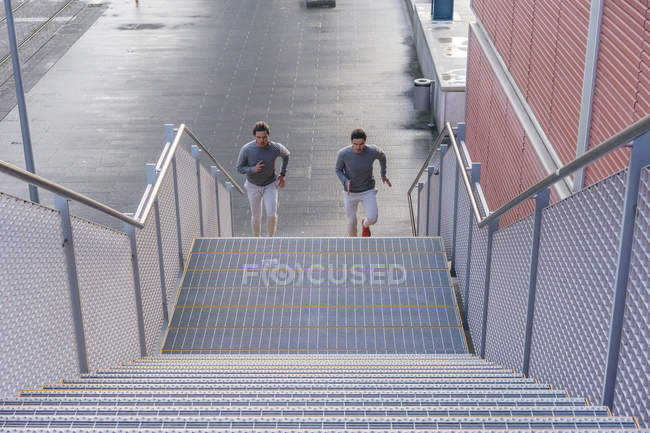 Jovens gêmeos do sexo masculino correndo até a escada da cidade — Fotografia de Stock