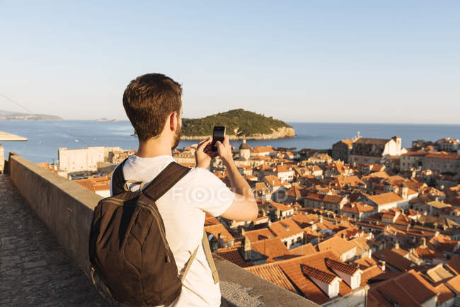 Homem fotografando mar sobre telhados em Dubrovnik, Dubrovacko-Neretvanska, Croácia, Europa — Fotografia de Stock