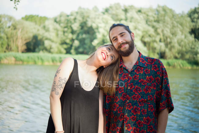 Retrato de una joven pareja sonriente junto al lago, Toscana, Italia - foto de stock