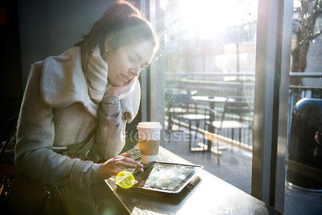 Giovane ragazza seduta in caffetteria, utilizzando tablet digitale, Londra, Inghilterra, Regno Unito — Foto stock