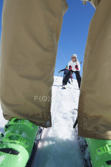 Skieurs vus à travers une paire de jambes — Photo de stock