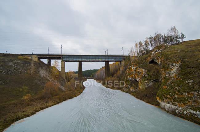 Paesaggio con ponte ferroviario sul fiume ghiacciato, Kislokan, Evenk, Russia — Foto stock