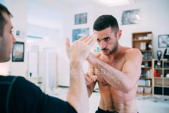Homme avec entraîneur personnel sparring en salle de gym — Photo de stock