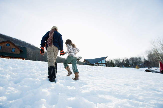 Вид сзади на брата и сестру, идущих по снегу — стоковое фото