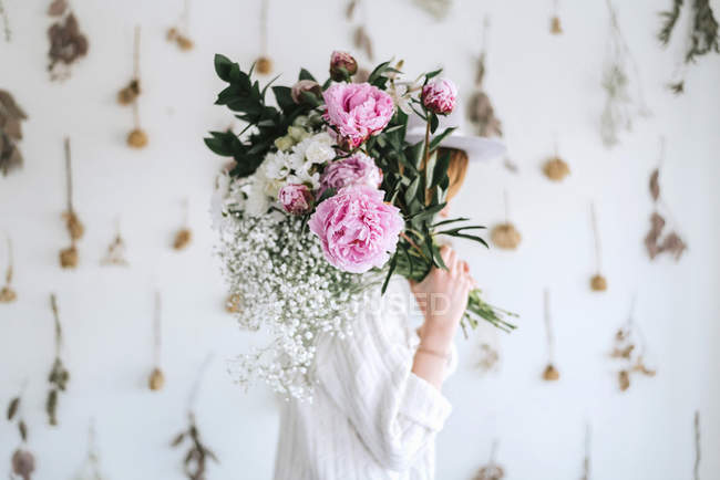 Woman covering face bunch of flowers — Stock Photo