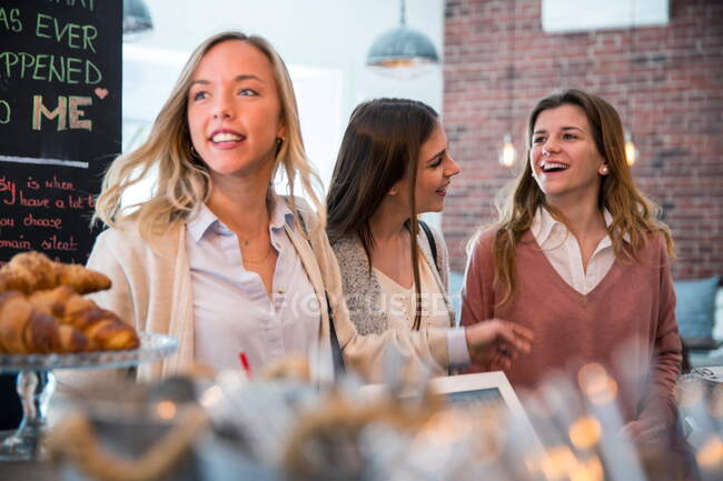 Three female friends in cafe, waiting to be served — Stock Photo