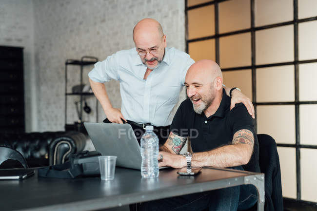 Колеги в офісі дивляться на ноутбук разом — стокове фото