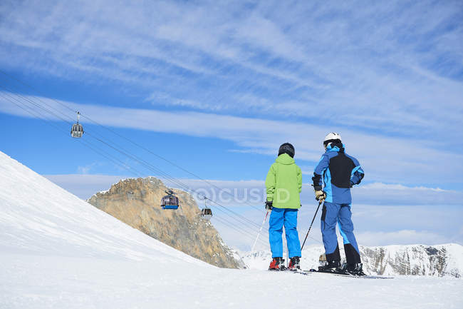 Vista trasera de padre e hijo en vacaciones de esquí, Hintertux, Tirol, Austria - foto de stock