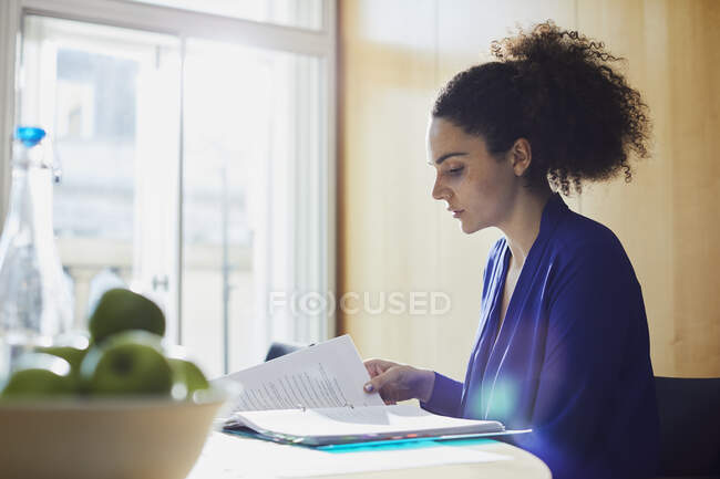 Jovem empresária lendo papelada na mesa de escritório — Fotografia de Stock