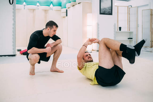 Man doing sit ups with personal trainer — Stock Photo