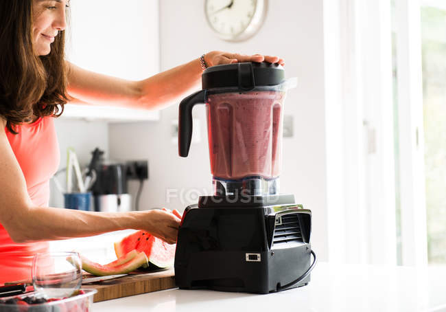 Side view of woman preparing smoothie in blender — Stock Photo