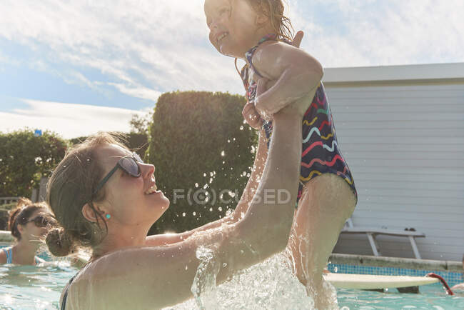 Woman holding toddler daughter up in swimming pool — Stock Photo