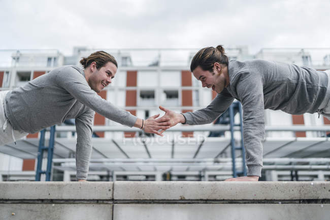 Young male twins training and doing one armed push ups — Stock Photo