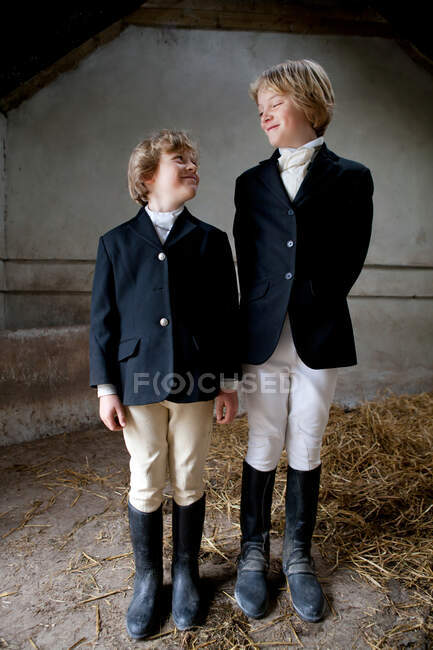 Garçons portant des vêtements d'équitation dans l'écurie — Photo de stock