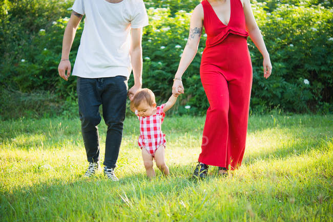 Couple with baby girl taking first steps in garden — Stock Photo