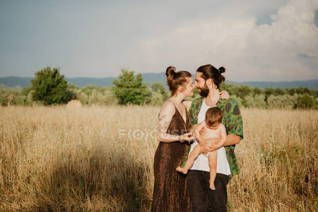 Parejas jóvenes con bebé en el campo de hierba dorada, Arezzo, Toscana, Italia - foto de stock