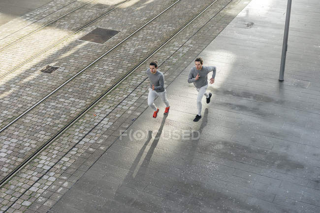 Young male twins running along sidewalk — Stock Photo
