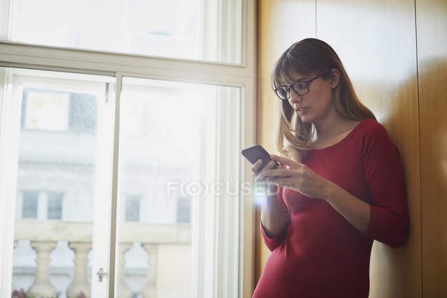 Geschäftsfrau schaut im Büro aufs Smartphone — Stockfoto