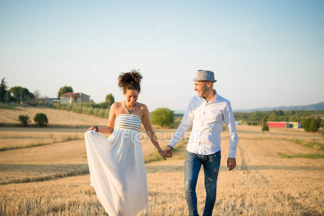 Couple marchant à travers le champ avec la main — Photo de stock