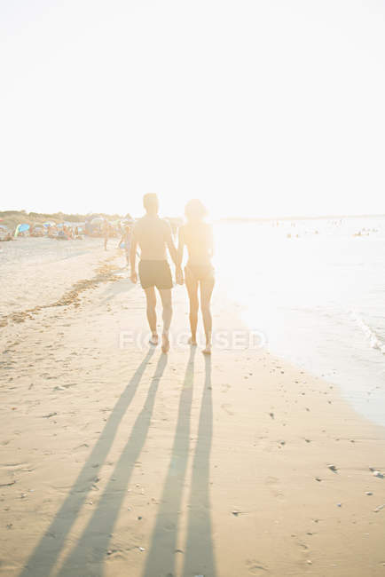 Rückansicht eines älteren Paares, das am Strand spaziert — Stockfoto