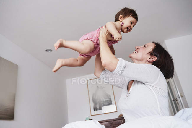 Mãe segurando bebê filha no ar — Fotografia de Stock