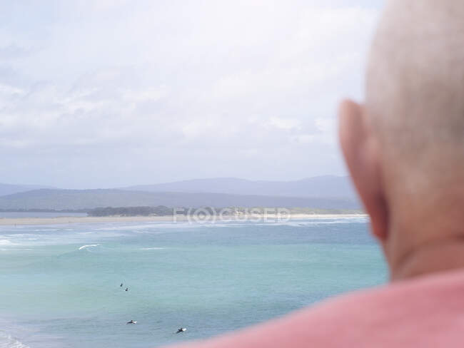 Hombre mayor mirando a la vista costera, vista trasera, Mallacoota, Victoria, Australia - foto de stock