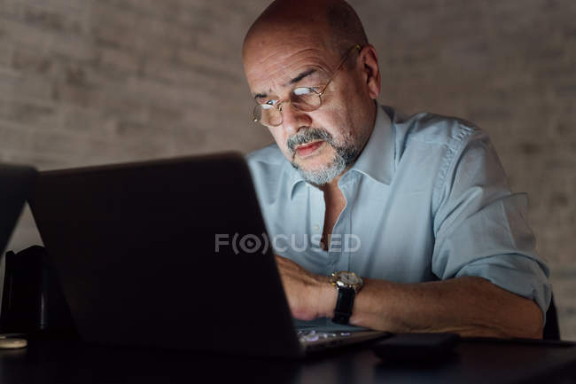 Senior man in eyeglasses using laptop — Stock Photo