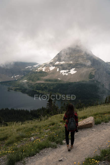 Rückansicht einer Frau, die in der Nähe eines versteckten Sees steht, Gletscher-Nationalpark, Montana, USA — Stockfoto