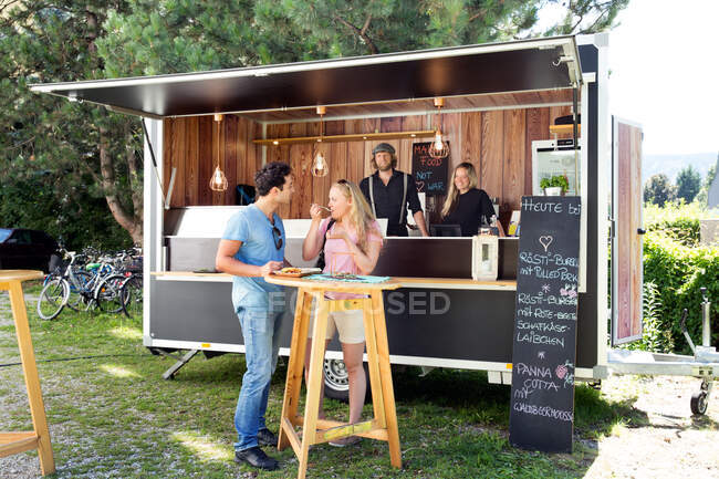 Clientes disfrutando de comida en food truck, Innsbruck Tirol, Austria - foto de stock
