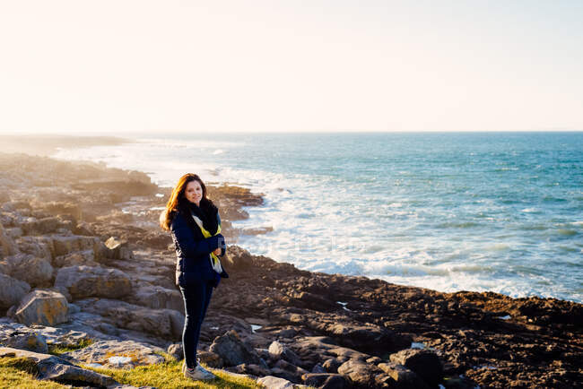 Mujer caminando por el mar, Fanore, Clare, Irlanda - foto de stock